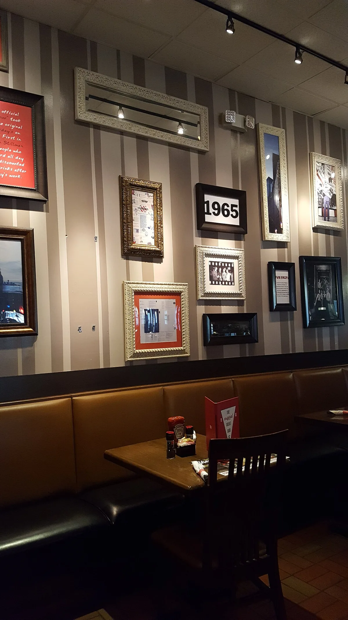 Muur met verschillende ingelijste foto's en decoratieve fotolijsten in een restaurantinterieur